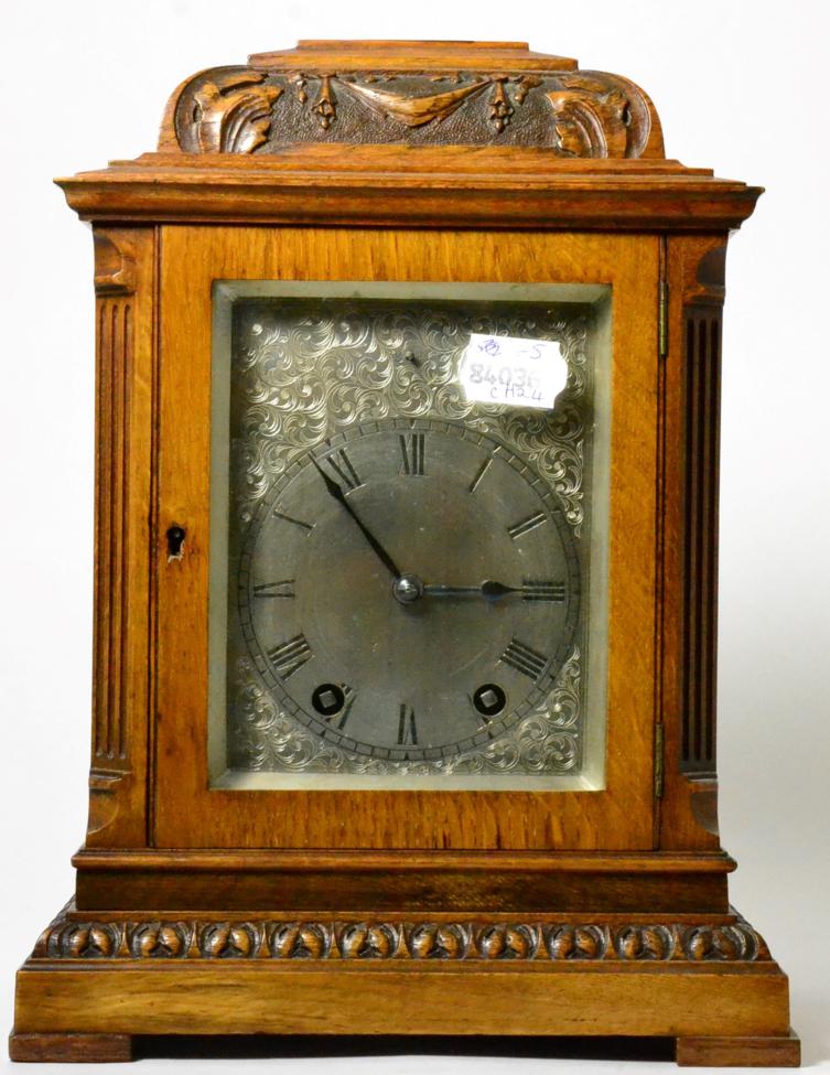 An oak striking carved mantel clock, circa 1910, inverted pediment, side sound frets, silvered