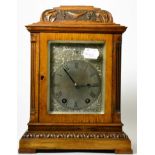 An oak striking carved mantel clock, circa 1910, inverted pediment, side sound frets, silvered