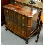A small stinkwood chest of drawers, the front of serpentine form, raised on four ball and claw feet