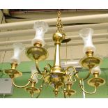 A brass six branch chandelier with glass shades