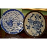 A Chinese blue and white charger featuring a dragon within a brown etched border and another with