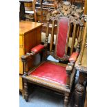 An impressive Victorian carved oak open armchair with studded leather slat seat and arms, and with