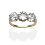 A Diamond Three Stone Ring, graduated old cut diamonds in white claw settings, to yellow scroll
