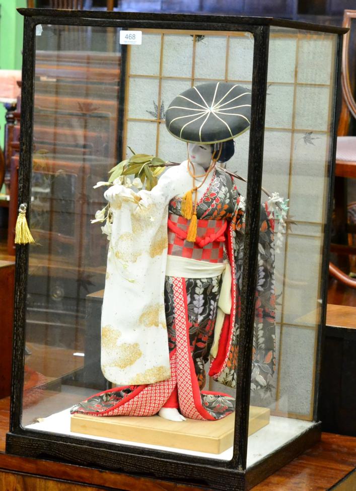 Japanese geisha girl dressed in traditional robes enclosed within table display case