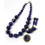 A lapis lazuli graduated bead necklace, a pair of lapis lazuli earrings, a brooch and a pair of