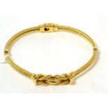 A fancy rope and knot design bangle, stamped '750' 34.13g gross