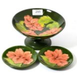 Walter Moorcroft coral Hibiscus comport and two pin dishes, on a green ground (3)