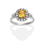 An 18 Carat White Gold Yellow Sapphire and Diamond Ring, an oval cut yellow sapphire in a claw