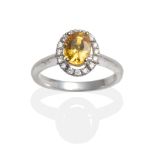 An 18 Carat White Gold Yellow Sapphire and Diamond Cluster Ring, an oval cut yellow sapphire in a