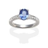 An 18 Carat White Gold Sapphire and Diamond Ring, an oval cut sapphire in a claw setting, to diamond