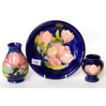 Walter Moorcroft Magnolia pattern plate and two vases on blue grounds (3)