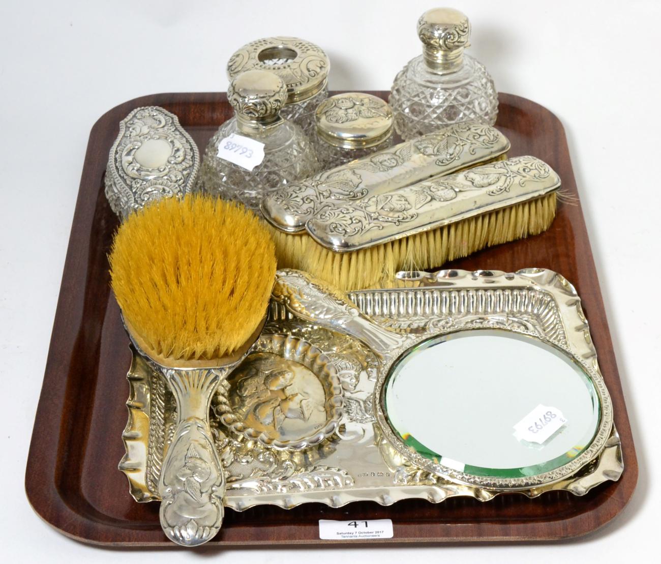 A silver dressing table set including tray, decorated with putti, together with other dressing table