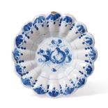 A Delft Dish, circa 1700, of fluted circular form, painted in blue with fruit within a foliate