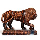 ~ A Treacle Glazed Pottery Figure of a Lion, 19th century, its forepaw on a globe, on a stepped