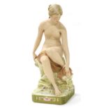 A Royal Dux Bisque Porcelain Figure of a Bather, early 20th century, sitting on a rock drying her
