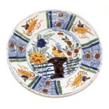 A Delft Pancake Plate, circa 1760, painted in colours with a bird amongst foliage and rockwork