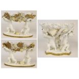 A Moore Glazed Parian Three Piece Garniture, circa 1880, modelled as shells supported by putti on