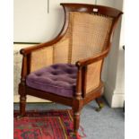 ~ A Regency Mahogany Bergere, early 19th century, the single cane back and sides above a purple