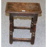 A 17th Century Joined Oak Back Stool, the four-pegged moulded top above turned gun barrel supports