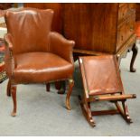 ^ An Early 20th Century Armchair, upholstered in close-nailed brown leather, raised on cabriole