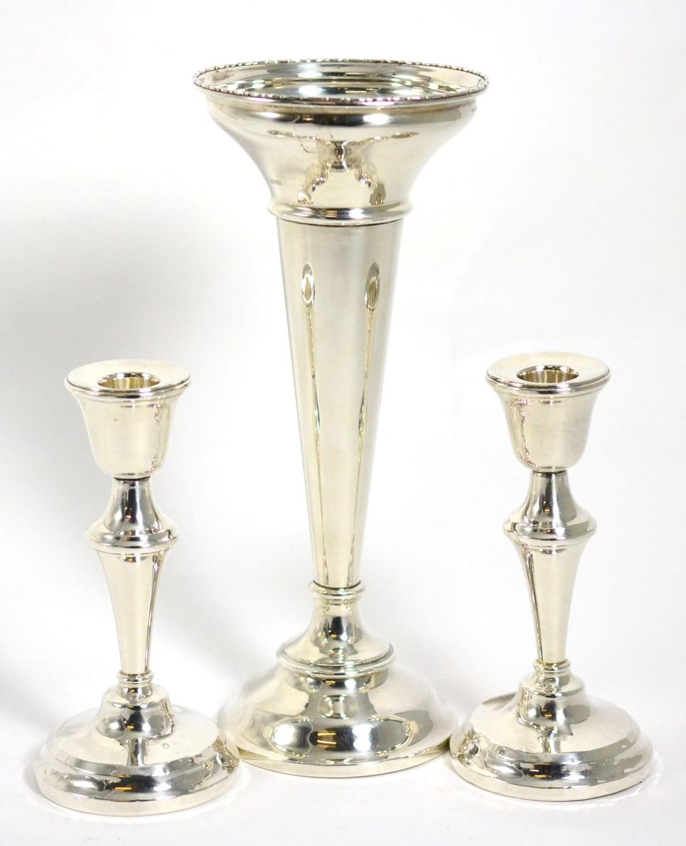 A large silver trumpet shaped vase; and a pair of silver candlesticks