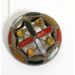 A Scottish hardstone brooch, a central cross motif within a circular frame and set throughout with