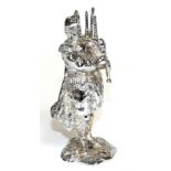 A Chrome Car Mascot Modelled as a Scottish Piper, standing on a rocky base with drill hole, 15cm