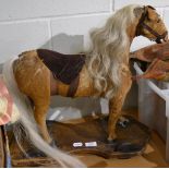 Late 19th century hide covered pull-along horse on a shaped pine base and metal wheels