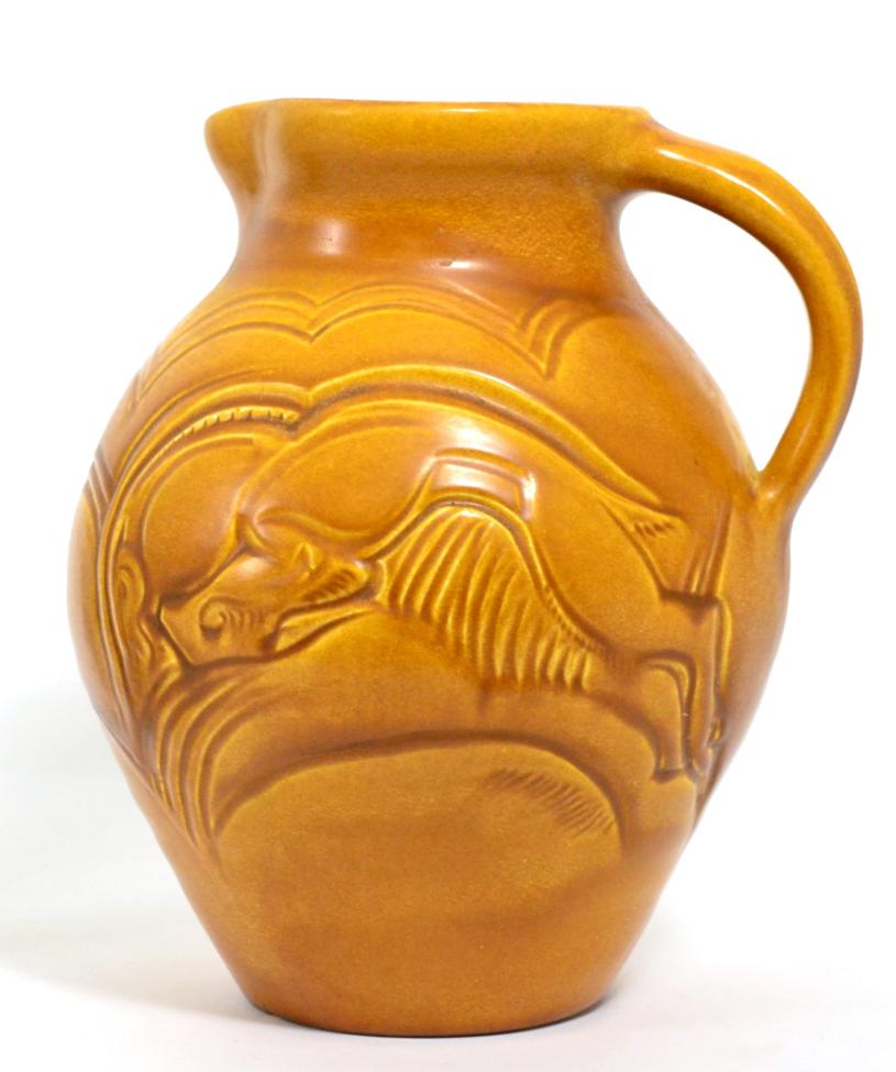 A Susie Cooper Carved Ware jug, incised with fighting gazelles, covered in a matt orange glaze,