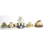 A Royal Crown Derby frog money box; together with four frog paperweights (three gold and one