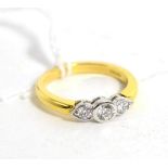 An 18 carat gold diamond three stone ring, round brilliant cut diamonds in rubbed over settings,