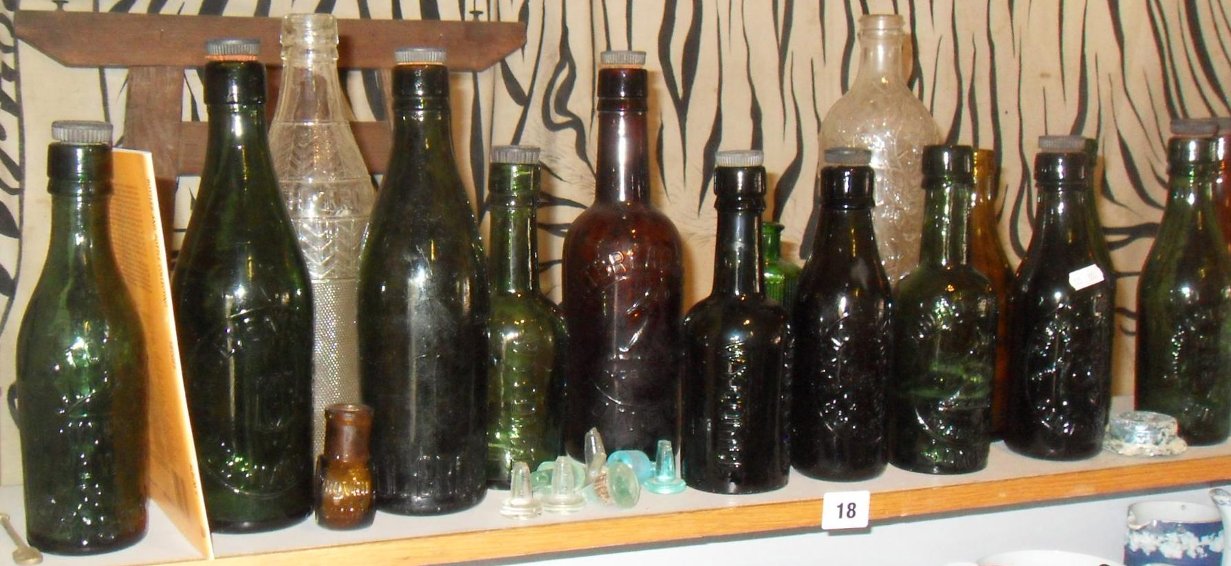 Shelf of old glass bottles with embossed brewery names (mainly West Country) associated book