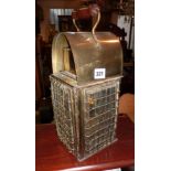 Old brass oil lantern with four glass doors covered with brass wire grill and carrying handle