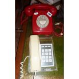 Vintage red plastic rotary dial telephone, 1960s, and a Betacom clear plastic-based telephone