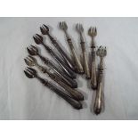 A collection of nine Indian silver pickle forks with ornate handles
