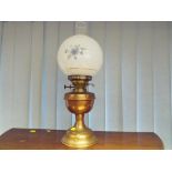 A brass and copper oil lamp with glass shade