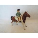 Beswick Pottery - a figurine depicting a girl seated on a piebald pony,