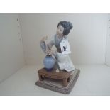 Lladro - a figurine depicting a Japanese girl / Geisha kneeling arranging flowers, 19 cm (high),