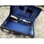 A black case with fitted interior containing a 15-piece vanity set with hallmarked silver mounts,