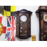 A decorative polished wood-cased wall clock, the case with opening glazed door,