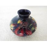 Moorcroft Pottery - a squat vase decorated with orchids on a cobalt blue ground, 6.