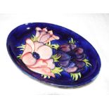 Moorcroft Pottery - an oval dish decorated with anemone on a cobalt blue ground, approx 16.