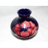 Moorcroft Pottery - a small squat vase decorated with anemone on a cobalt blue ground,