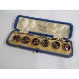 A cased set of six yellow metal dress buttons decorated with stitch motifs