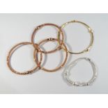 A collection of bangles; three rose gold