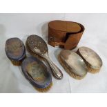Five hallmarked silver hairbrushes, two of which contained in a leather case,