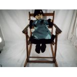 A good quality child's wooden rocking chair with a child's doll with papier mache head,