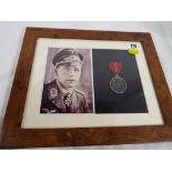 A framed picture of a German soldier and a medal (not belonging to this soldier) mounted and framed.
