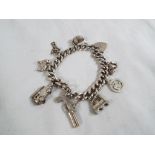 Silver - a silver curb charm bracelet with eight silver charms, safety chain and silver padlock.