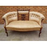 A Victorian mahogany upholstered settee with carved back rest.
